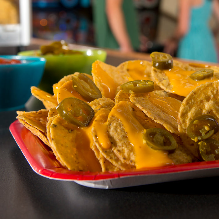 Plate of nachos covered in cheese sauce and jalapeno slices.