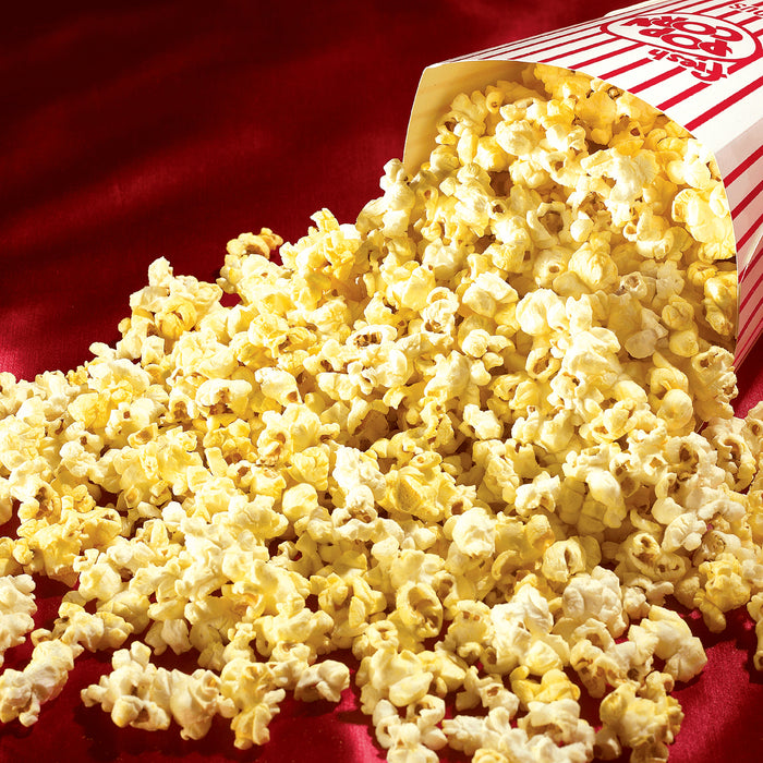 movie theater popcorn pouring out of a red and white striped bucket on a red background